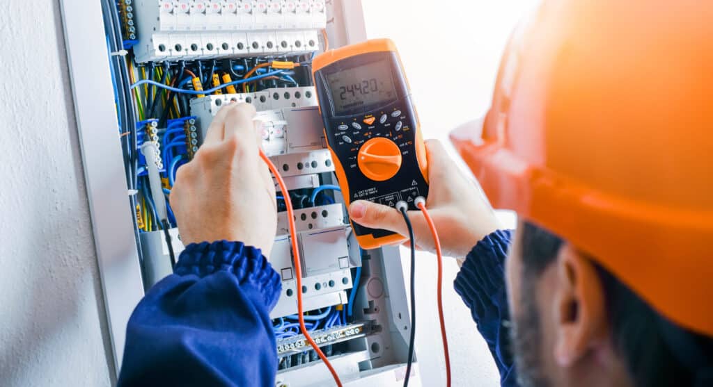 Électricien: Mesure et sécurité du tableau électrique Électricien mesurant la tension (244.20 V) sur un tableau électrique résidentiel avec disjoncteurs "B 16" et câbles. Sécurité.